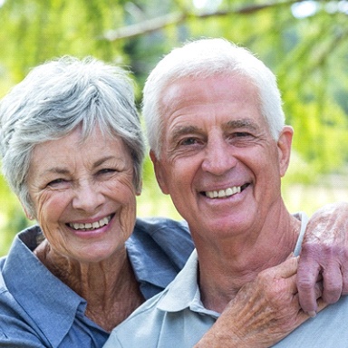 An older couple smiling outside.